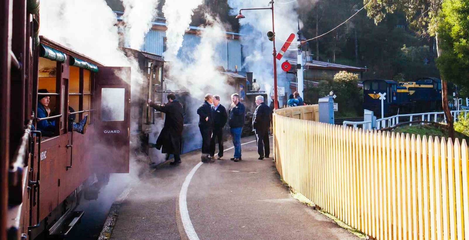 people standing on train platform next to puffing billy