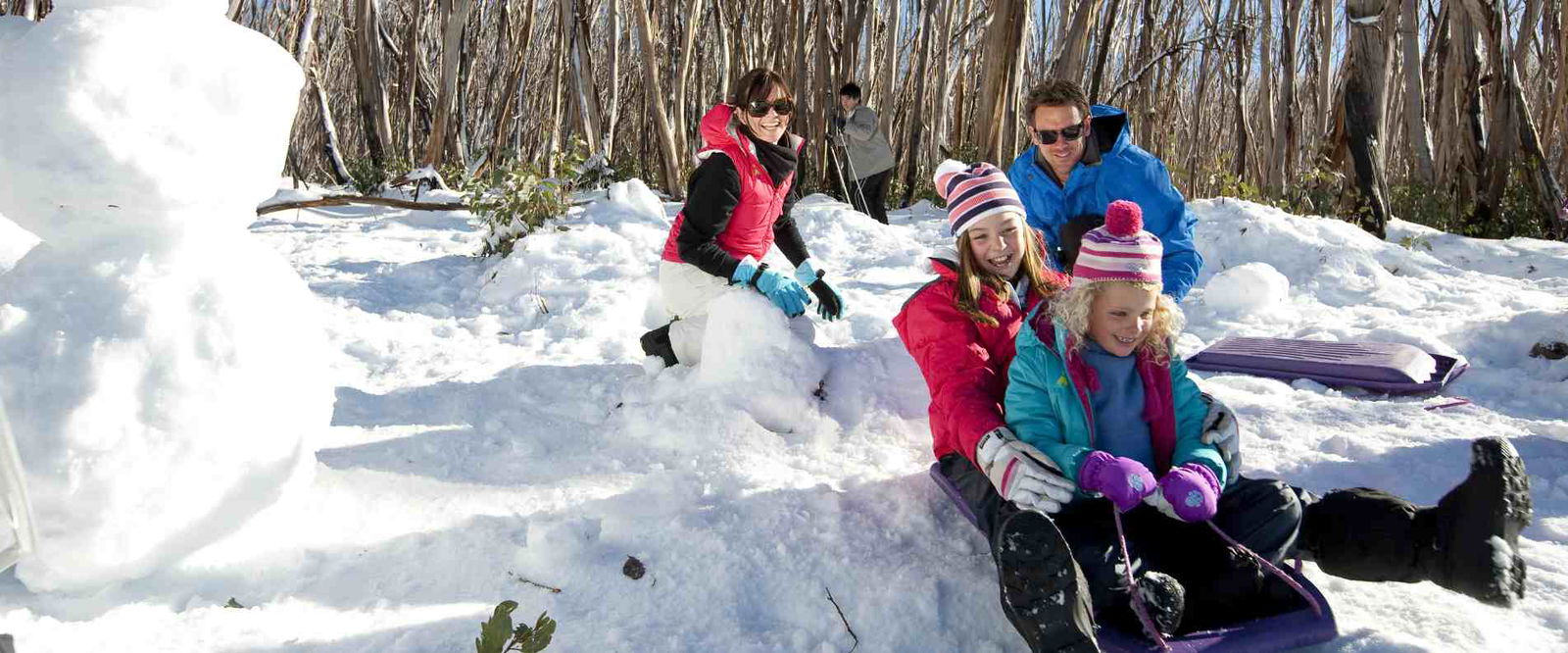 Family playing in the snow and Tobogganing at lake mountain