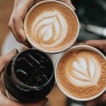 3 people holding coffee cups together in circle