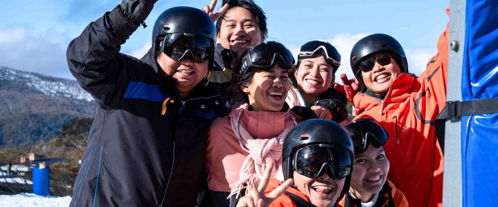  A group of individuals in ski gear smiling and posing together for a photo in a snowy landscape.